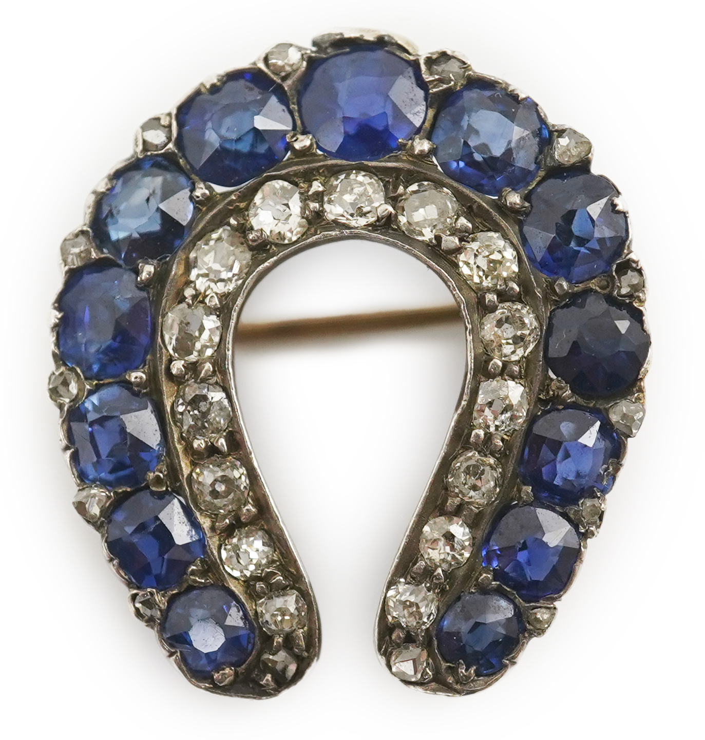 An Edwardian, gold and silver, diamond and sapphire set ‘horse shoe’ brooch